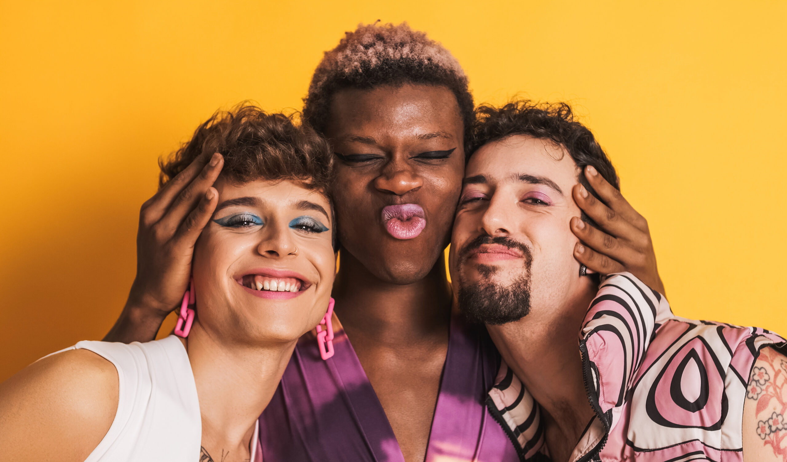 Three smiling people against a yellow backdrop