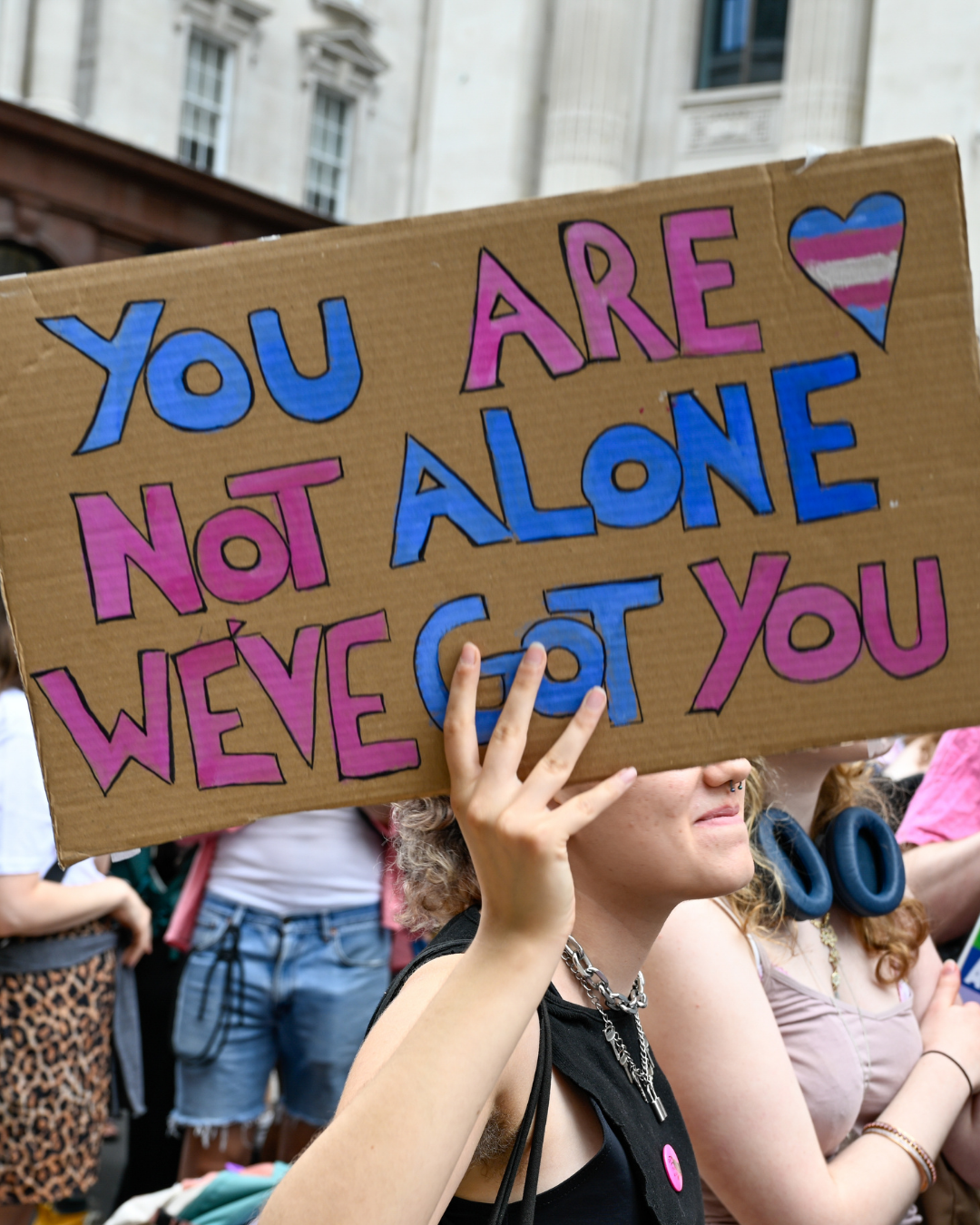 A Person in a crowd hosting a sign that says- You are not alone. We've got you.